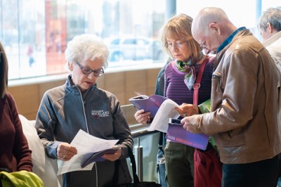 3 personnes qui consultent la brochure de saison du MIFO