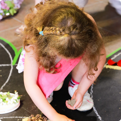 Enfant qui crée une oeuvre au sol avec des matériaux naturels