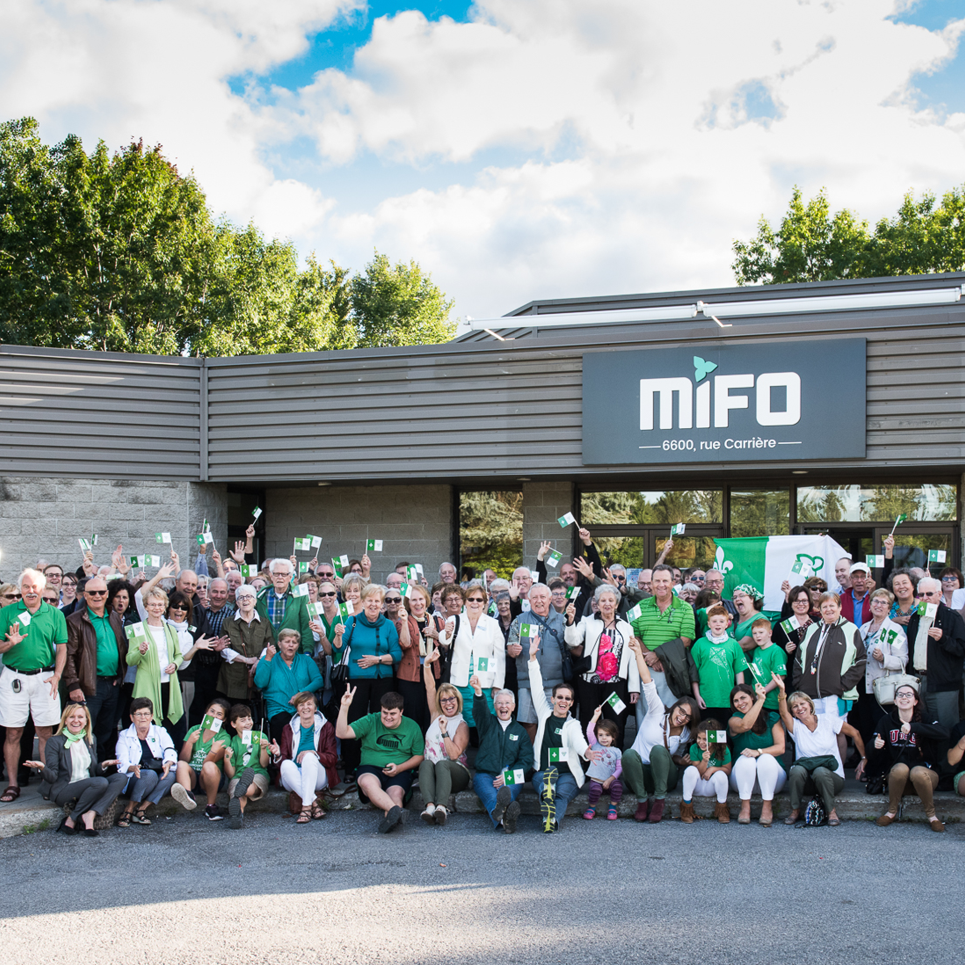 Groupe de personnes avec des drapeaux franco-ontariens devant le MIFO
