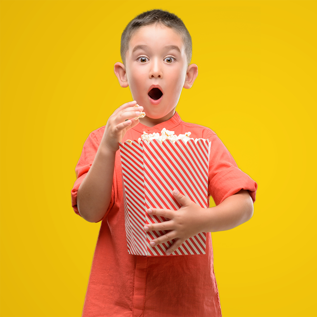 Enfant qui mange du maïs soufflé devant un arrière-plan jaune